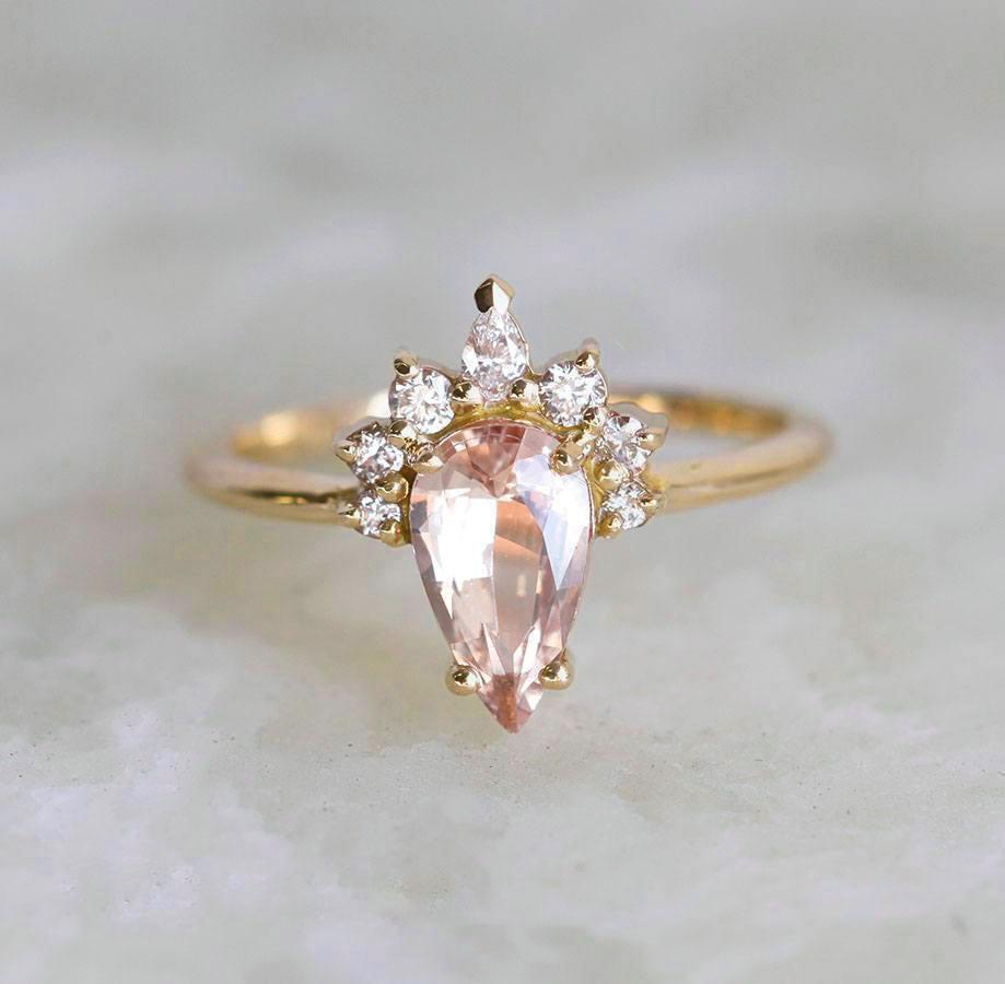 Pear-shaped peach sapphire ring with diamond halo