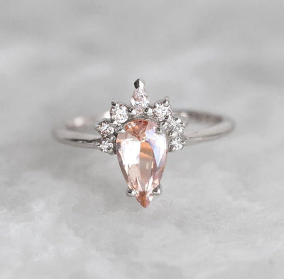 Pear-shaped peach sapphire ring with diamond halo