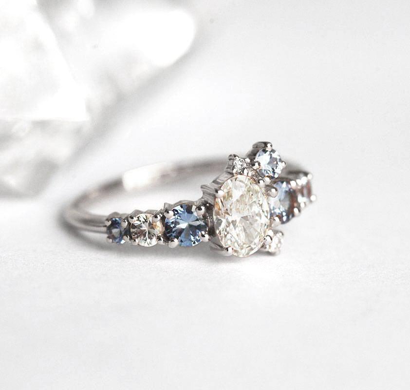 Oval-shaped white diamond cluster ring with sapphires