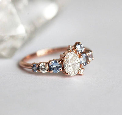 Oval-shaped white diamond cluster ring with sapphires