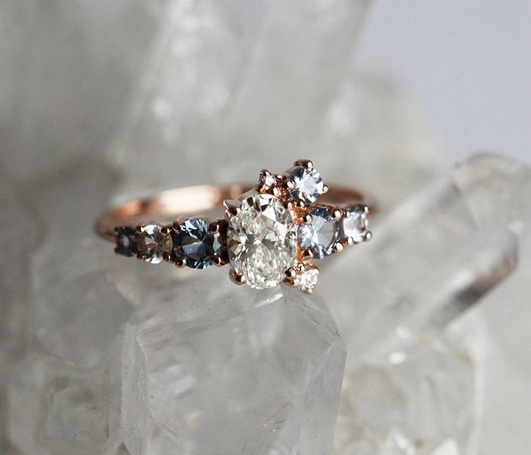 Oval-shaped white diamond cluster ring with sapphires