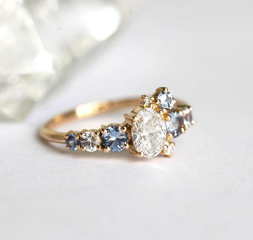 Oval-shaped white diamond cluster ring with sapphires