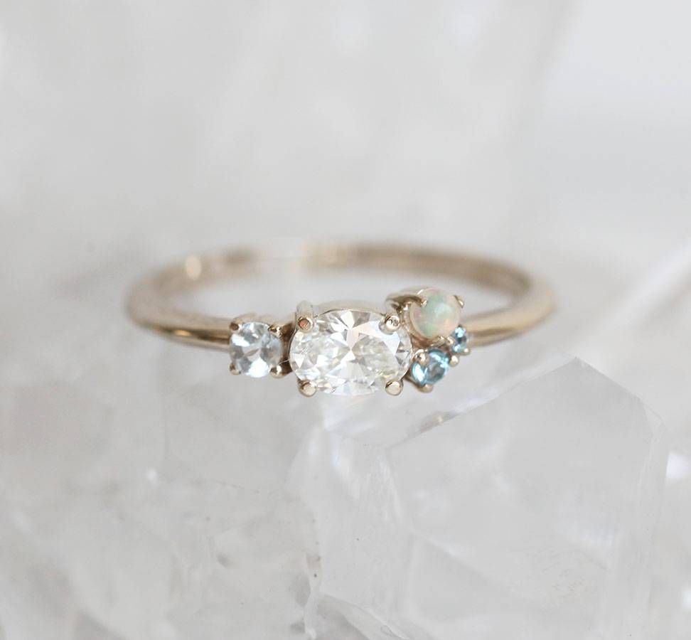 Oval-shaped white diamond cluster ring with sapphire, opal and topaz stones