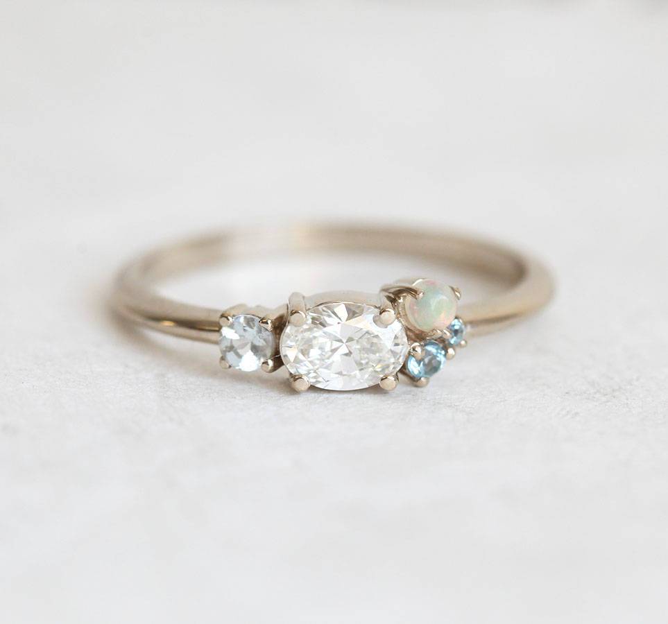 Oval-shaped white diamond cluster ring with sapphire, opal and topaz stones