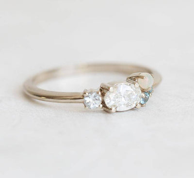 Oval-shaped white diamond cluster ring with sapphire, opal and topaz stones