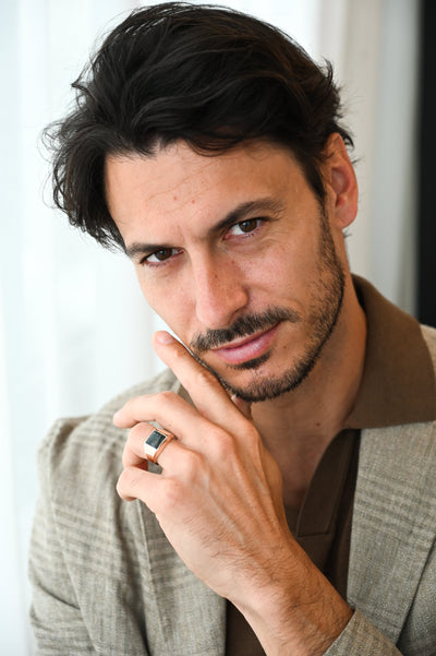 A man with a beard and mustache wearing a Moss Agate Signet Ring in gold and platinum.