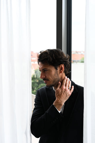 A man in a suit with a goldstone signet ring on his chin, showcasing the Goldstone Signet Ring.