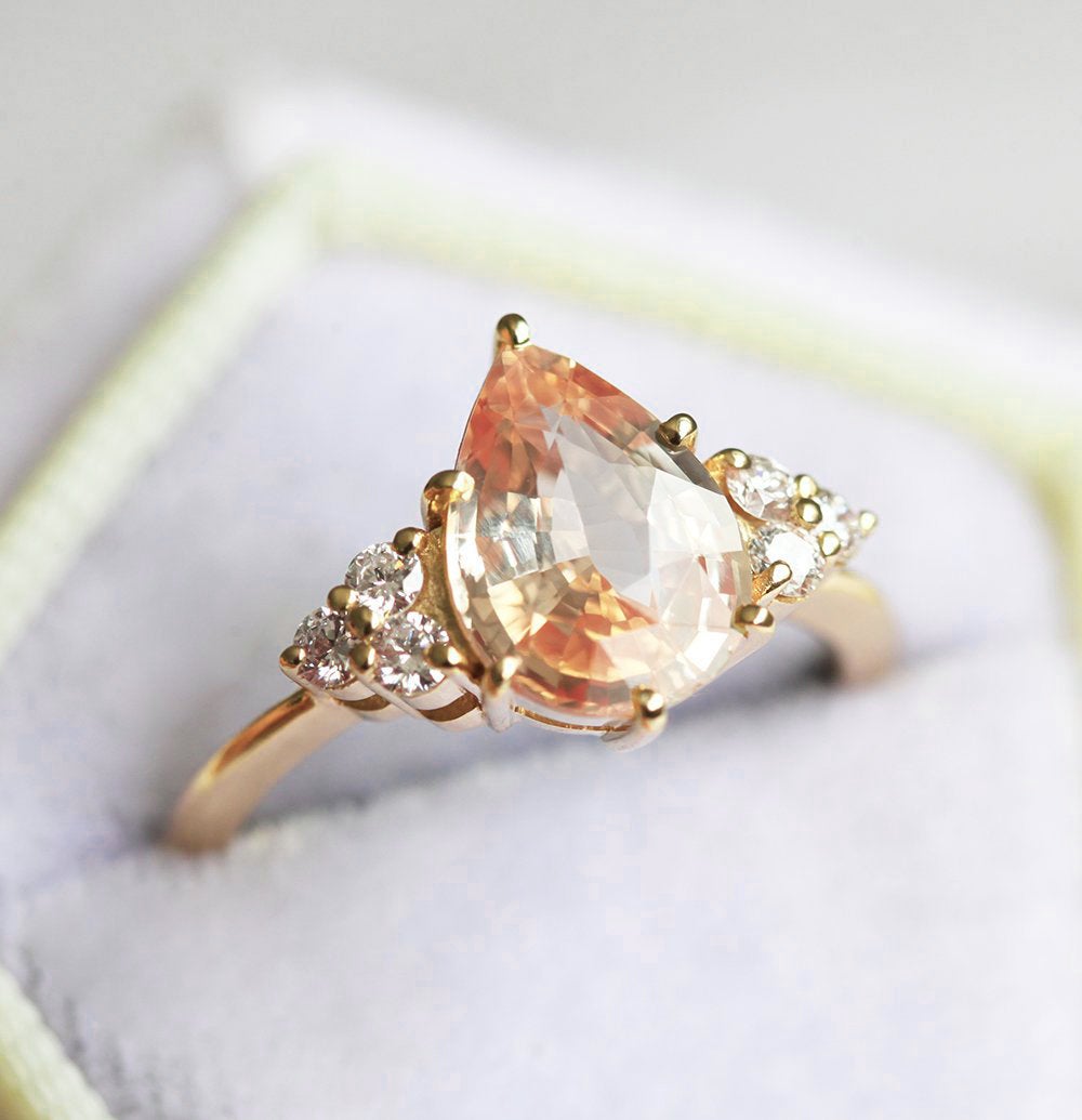 Pear-shaped peach sapphire ring with diamond cluster