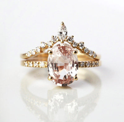 Oval-shaped peach sapphire ring with diamond cluster