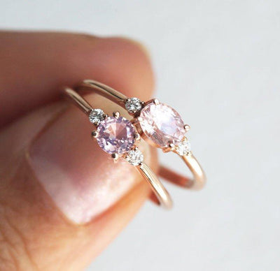 Oval-shaped pink peach sapphire ring with white side diamonds