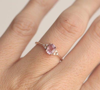 Oval-shaped peach pink sapphire ring with white side diamonds