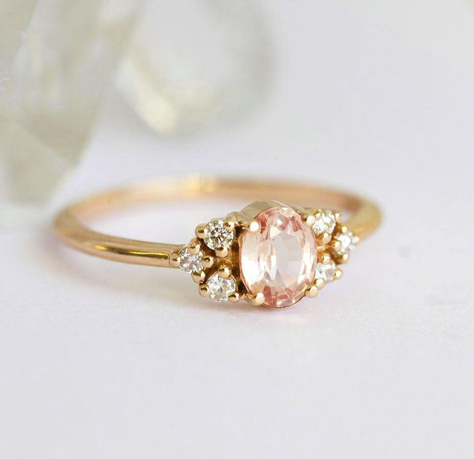 Oval-shaped peach sapphire ring with white diamond cluster