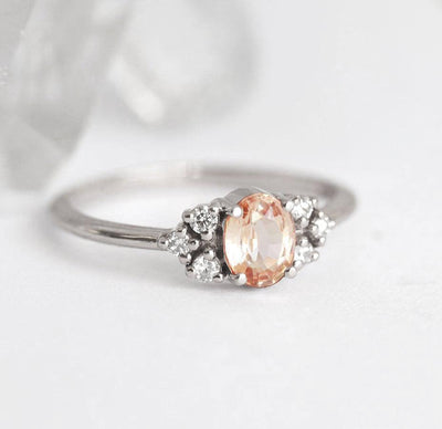 Oval-shaped peach sapphire ring with white diamond cluster