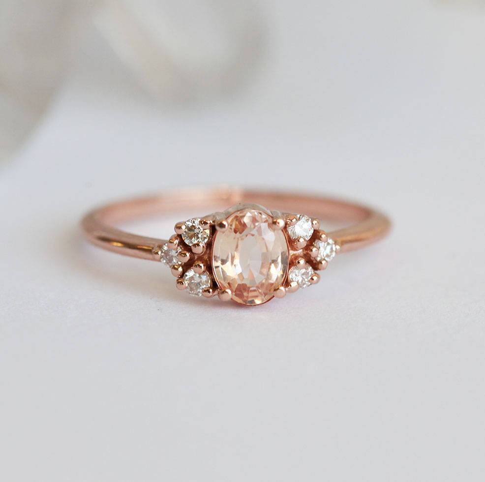 Oval-shaped peach sapphire ring with white diamond cluster