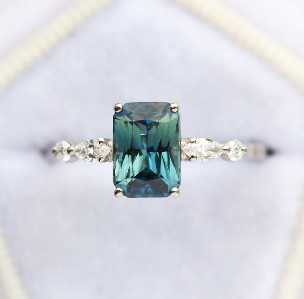 Radiant teal sapphire ring with white side diamonds