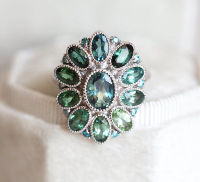 Oval-shaped teal sapphire cluster ring with torumaline and blue diamond stones