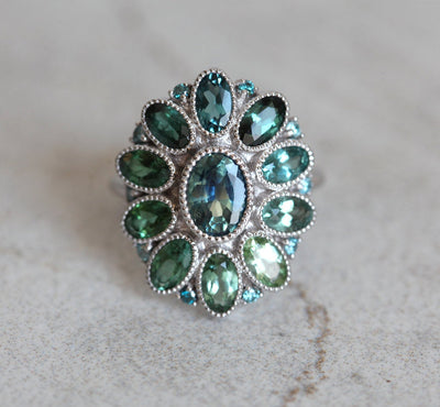 Oval-shaped teal sapphire cluster ring with torumaline and blue diamond stones