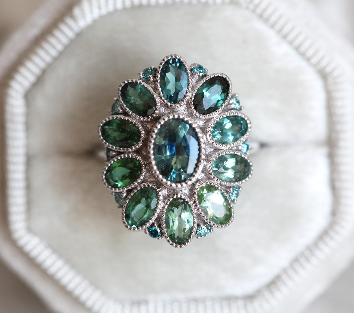 Oval-shaped teal sapphire cluster ring with torumaline and blue diamond stones