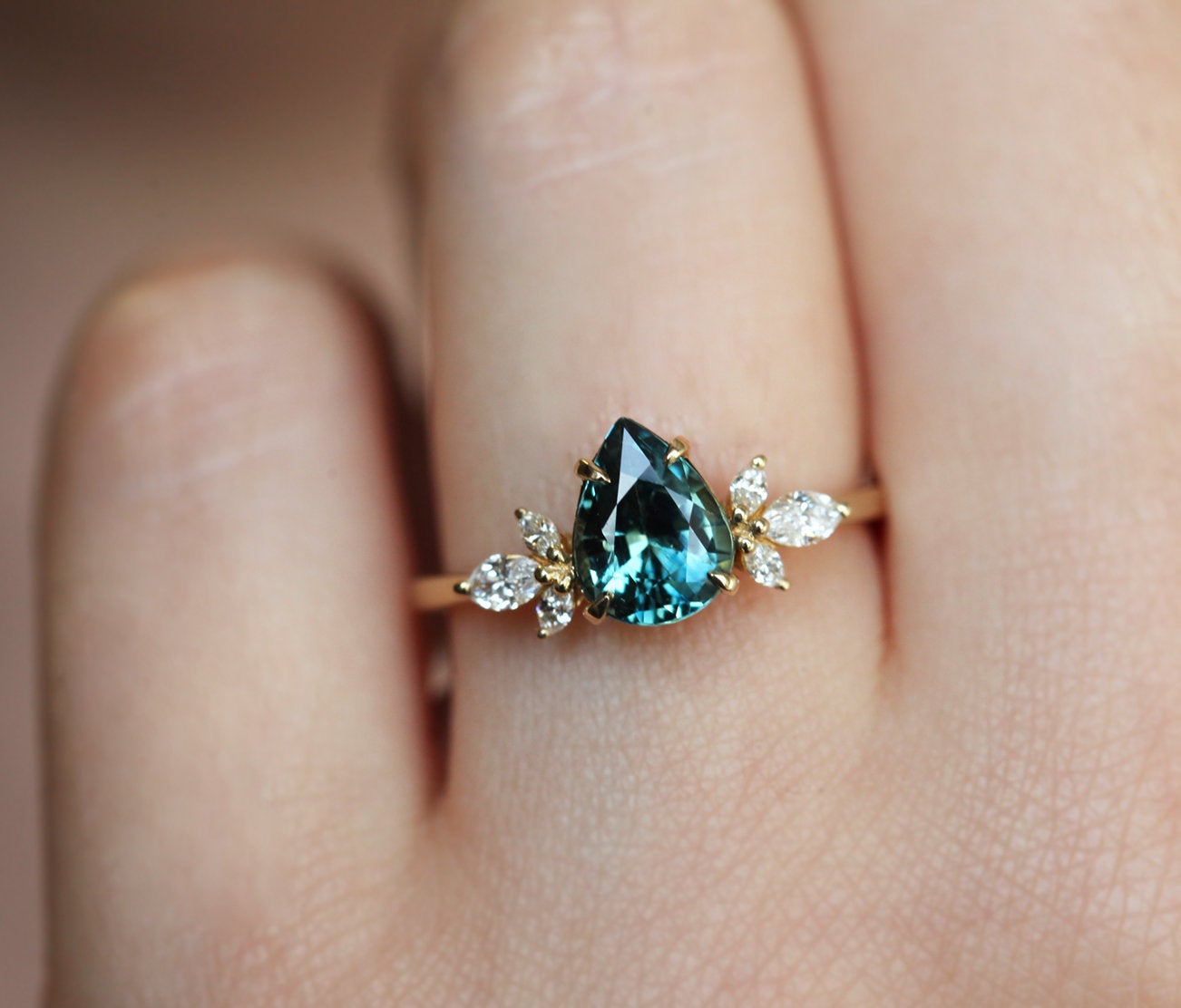 Pear-shaped teal sapphire ring with diamond cluster