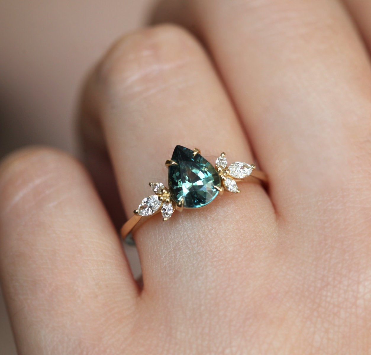 Pear-shaped teal sapphire ring with diamond cluster