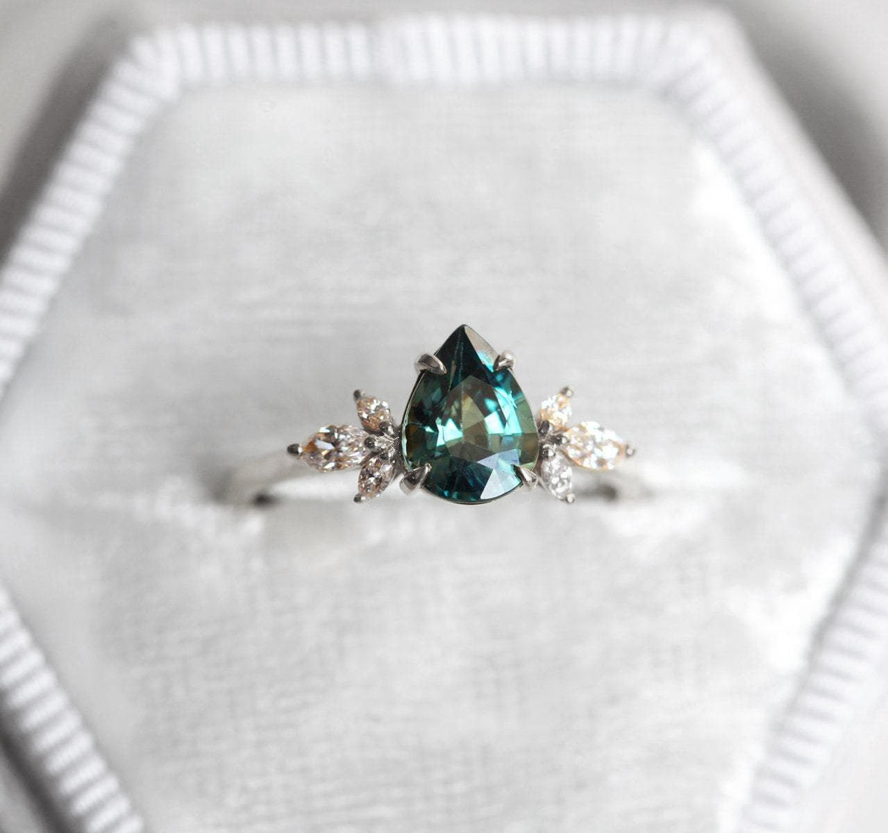 Pear-shaped teal sapphire ring with diamond cluster