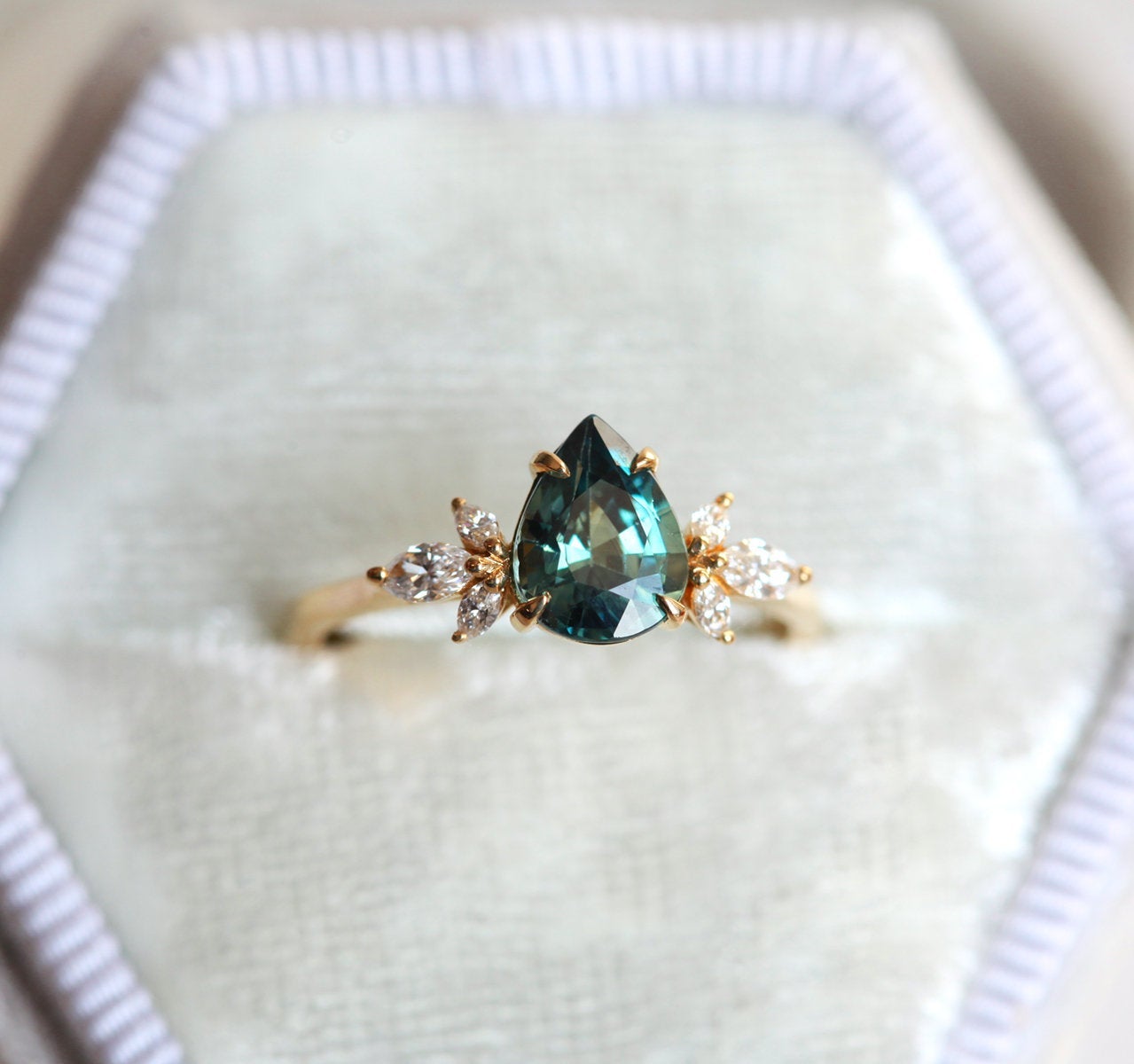 Pear-shaped teal sapphire ring with diamond cluster