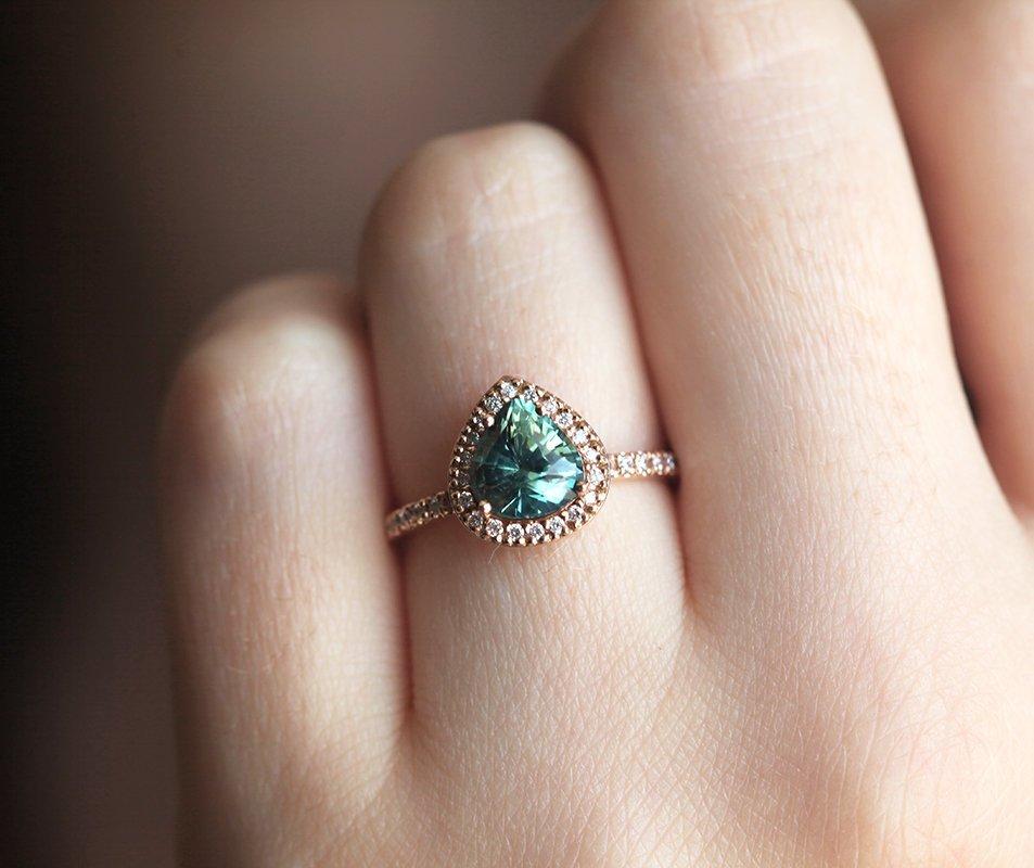 Pear-shaped teal green sapphire ring with diamond halo
