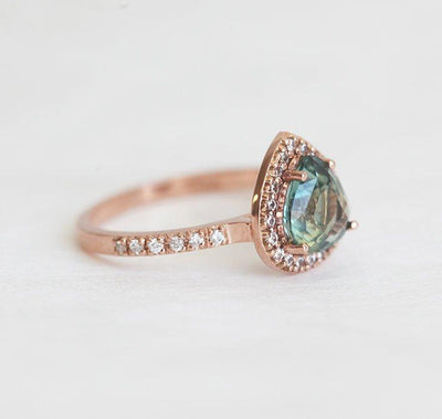 Pear-shaped teal green sapphire ring with diamond halo