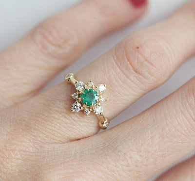 Emerald ring on hand with diamond halo, design in 14k gold.