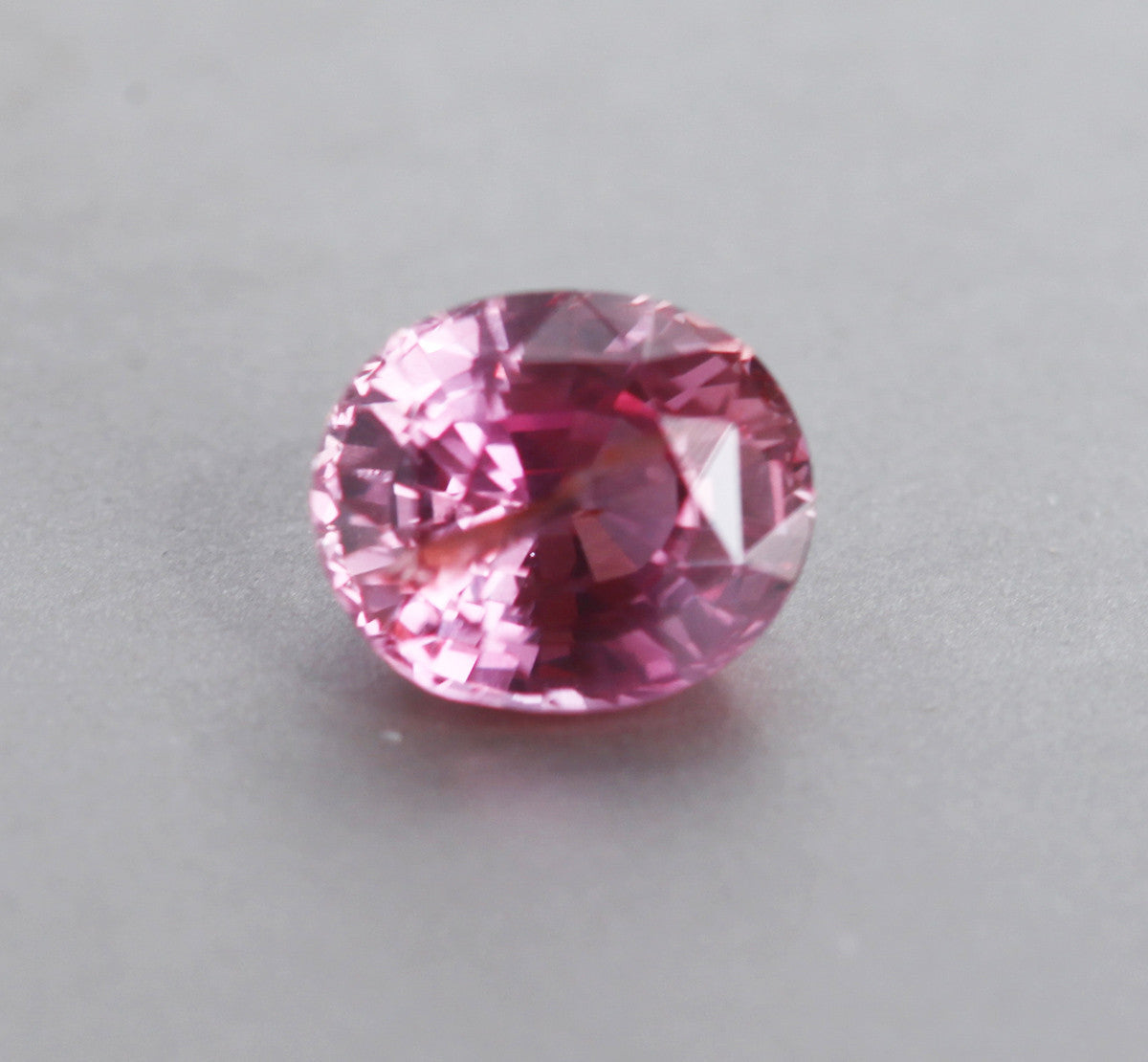 Loose oval-shaped orange pink sapphire