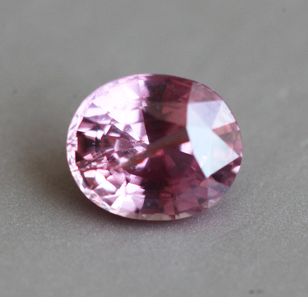 Loose oval-shaped orange pink sapphire
