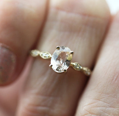 Oval-shaped peach sapphire with diamond cluster