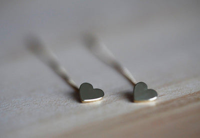 Heart-shaped gold stud earrings with dangling chain