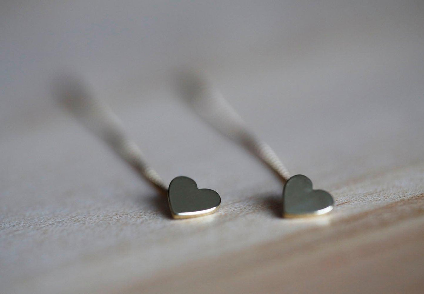 Heart-shaped gold stud earrings with dangling chain