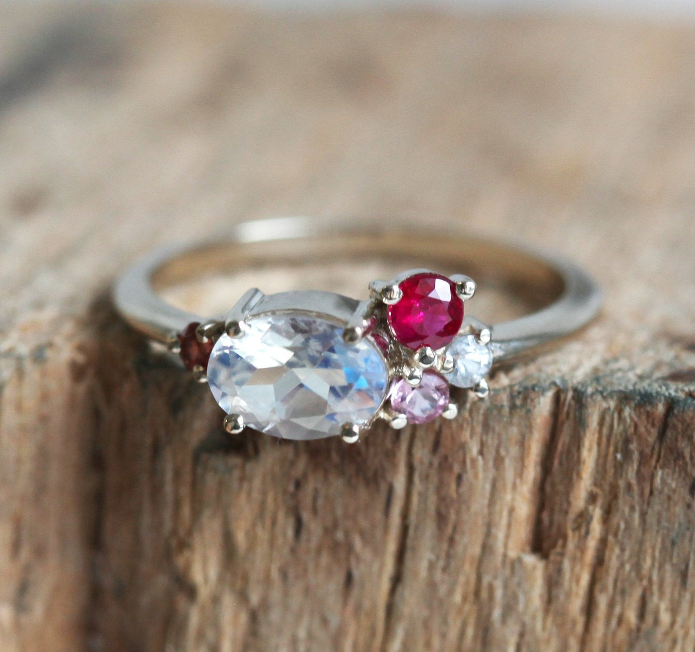 Oval-shaped white moonstone cluster ring with ruby, garnet and sapphire stones