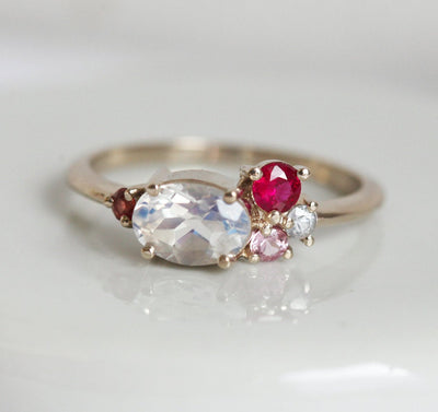 Oval-shaped white moonstone cluster ring with ruby, garnet and sapphire stones
