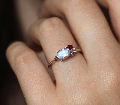 Oval-shaped white moonstone cluster ring with ruby, garnet and sapphire stones