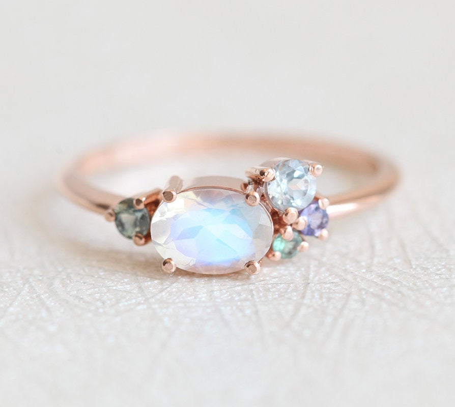 Oval-shaped white moonstone cluster ring with ruby, garnet and sapphire stones