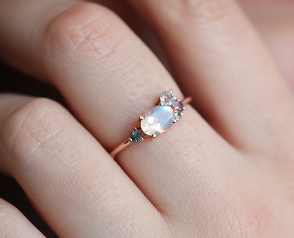 Oval-shaped white moonstone cluster ring with ruby, garnet and sapphire stones