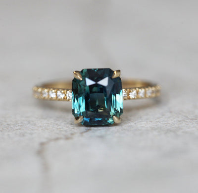 Radiant-cut teal sapphire ring with white side diamonds