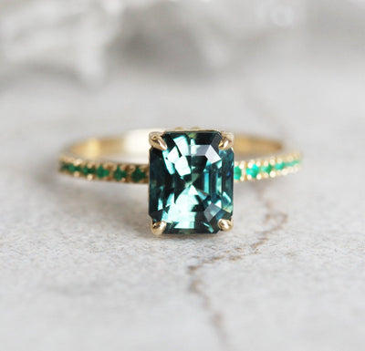 Radiant-cut teal sapphire ring with side emeralds