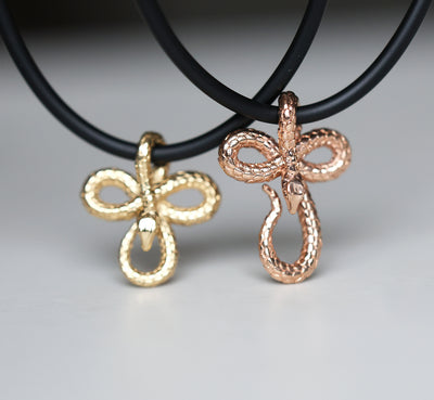 Two 14K gold snake pendant necklaces, featuring an intricate design on a sleek natural rubber cord—bold, symbolic, and effortlessly stylish.