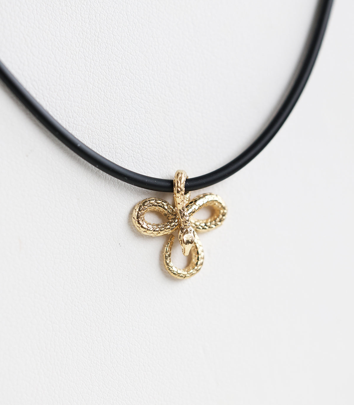 A 14K gold snake pendant necklace, featuring an intricate design on a sleek natural rubber cord—bold, symbolic, and effortlessly stylish.