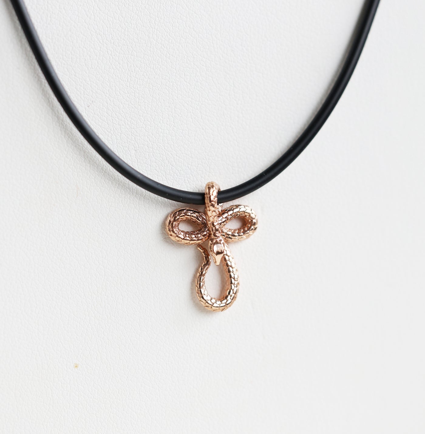 A 14K gold snake pendant necklace, featuring an intricate design on a sleek natural rubber cord—bold, symbolic, and effortlessly stylish.