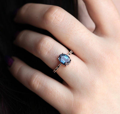 Teal Oval Alexandrite Ring with Side Blue Topaz Stones and Black Round Diamonds Nested in the Band