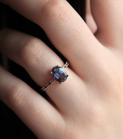 Teal Oval Alexandrite Ring with Side Blue Topaz Stones and Black Round Diamonds Nested in the Band