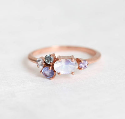 Oval moonstone cluster ring with aquamarine, sapphire, tanzanite and emerald stones