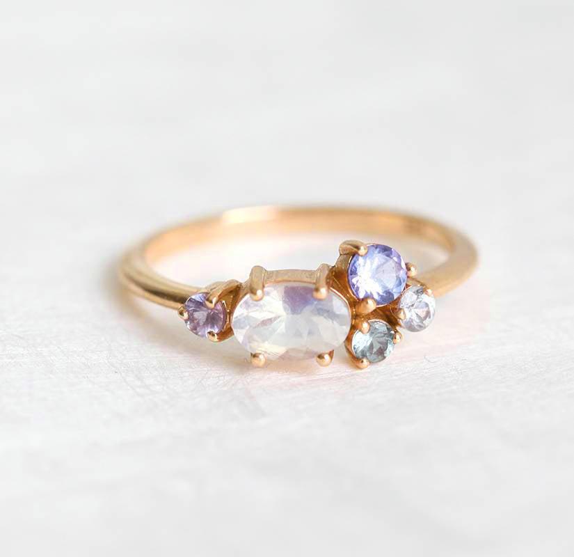 Oval moonstone cluster ring with aquamarine, sapphire, tanzanite and emerald stones