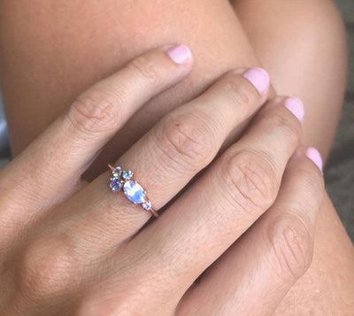 Oval moonstone cluster ring with aquamarine, sapphire, tanzanite and emerald stones