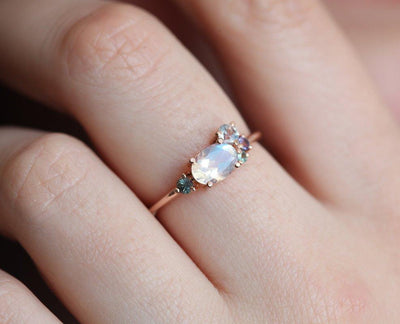 Oval moonstone cluster ring with aquamarine, sapphire, tanzanite and emerald stones